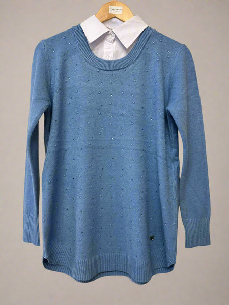 Blue sweater with a white shirt underneath on a hanger against a plain background